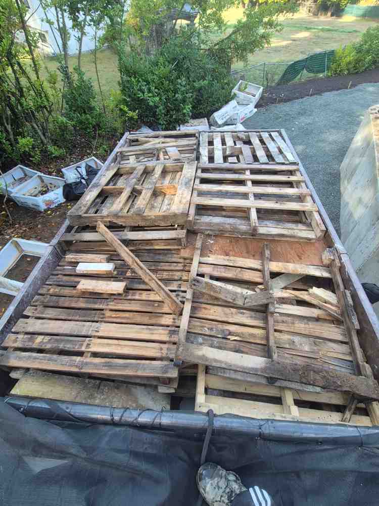 Redtree dump truck bed loaded full of wooden pallets at a job site